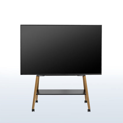 A large flat-screen display monitor on a wheeled easel TV stand with a black screen, slim black frame, and light wood legs, shown against a light gray gradient background.
