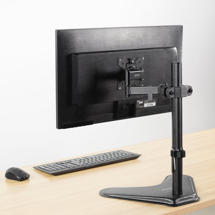 Pole Mount VESA Monitor Arm shown from the back on a light wood desk with a keyboard and mouse against a white background.