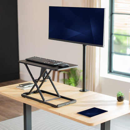 Adjustable standing desk with monitor, keyboard, and mouse setup in a home office.
